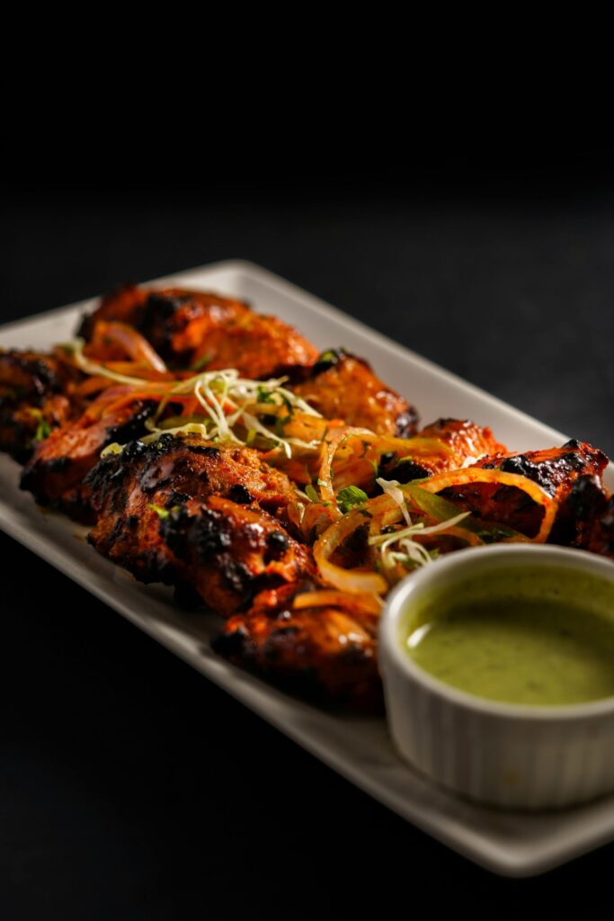 Thanduri chicken with fresh herbs and chili garnish